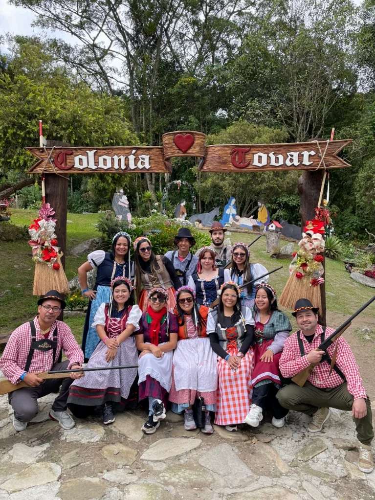 Viajeros con trajes típicos bajo el arco de la Colonia Tovar