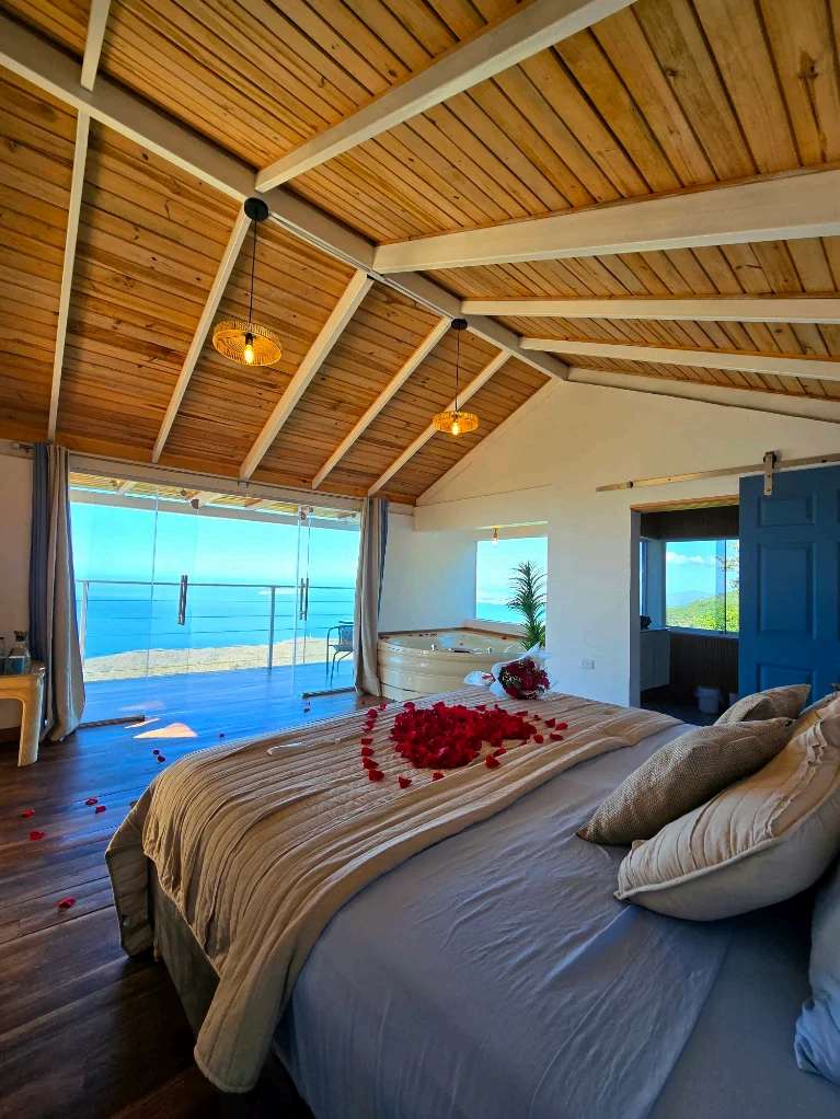 Habitación de glamping con techo de madera y ventanal abierto al mar