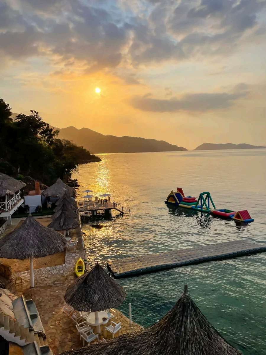 Atardecer dorado sobre Mochima con churuatas y un muelle flotante