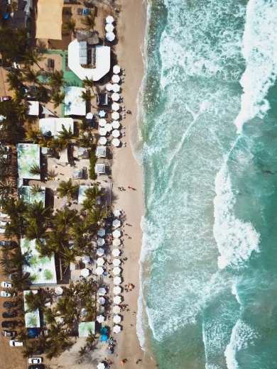 Vista aérea de una playa de arena blanca con oleaje turquesa