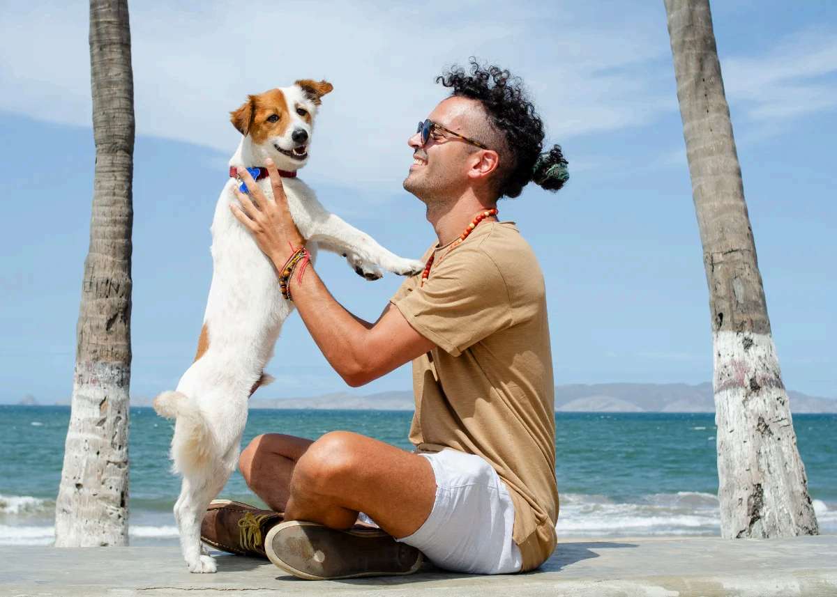 Viajero jugando con su perro en una playa de palmeras del oriente venezolano